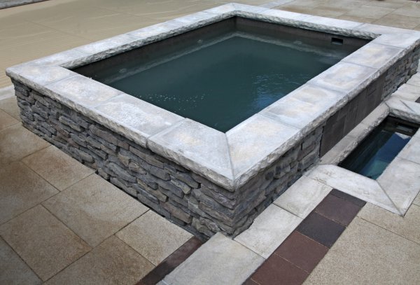 Custom hot tub by Unilock with Rivercrest wall